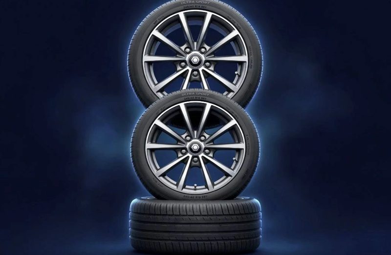 Two alloy wheels with tyres stacked on a third tyre