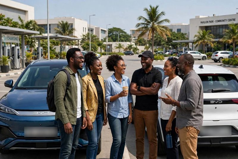 A group of EV owners laughing together beside their cars